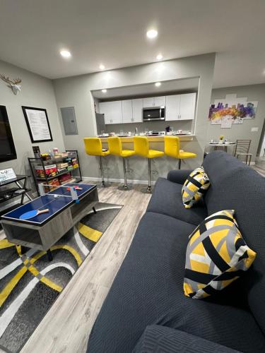 a living room with a blue couch and yellow stools at Games Haven with Crib Mins from AT&T, Sixflags, UTA, GlobeLife, AmericanAirlinesCenter in Arlington