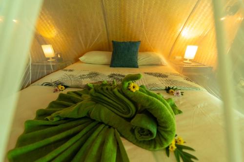 a green towel on a bed in a room at Bamboo Bay Eco Resort in Srithanu