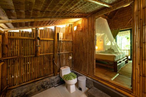 a bathroom with a toilet in a wooden room at Bamboo Bay Eco Resort in Srithanu