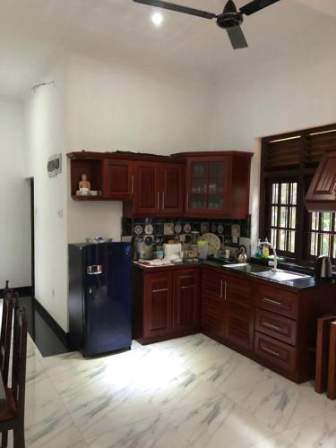 a kitchen with wooden cabinets and a black refrigerator at SRI LANKAN VILLA in Galle