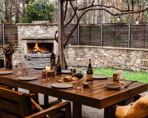 a wooden table with bottles of wine and a fireplace at Barn Haus in Margaret River Town