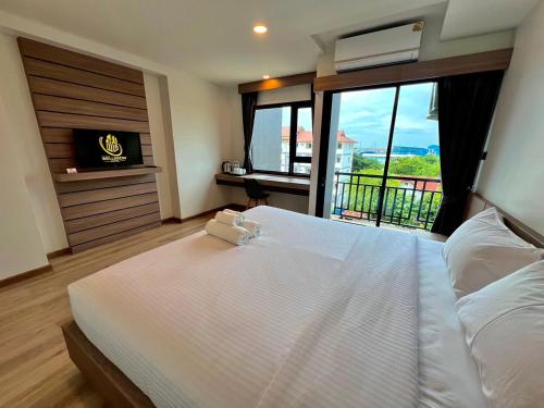 a bedroom with a large white bed with a balcony at เวลโกรว์ โฮเทล - Wellgrow Hotel in Ban Bang Kha