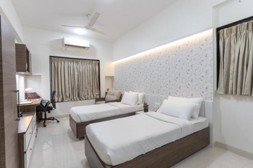 a hotel room with two beds and a desk at Bauhinia in Pune