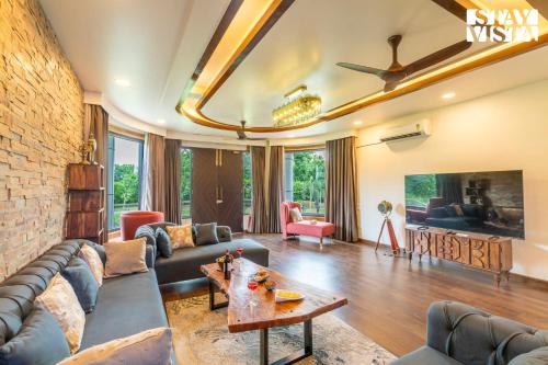 a living room with a couch and a brick wall at StayVista at Wandering Vines 4BHK with FREE Breakfast ,Indoor Pool in Delhi Sohna in Sohna