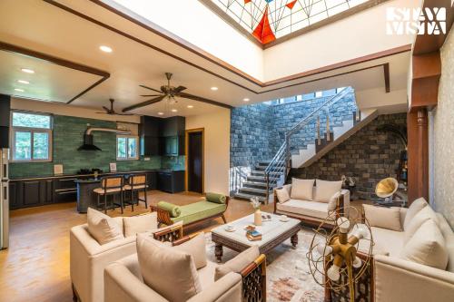 a living room with couches and a kitchen at StayVista at Wandering Vines 4BHK with FREE Breakfast ,Indoor Pool in Delhi Sohna in Sohna