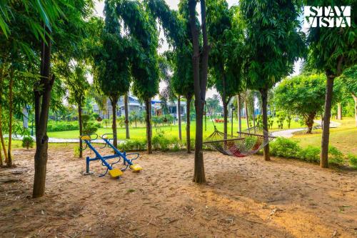 a park with swings and trees in a park at StayVista at Wandering Vines 4BHK with FREE Breakfast ,Indoor Pool in Delhi Sohna in Sohna