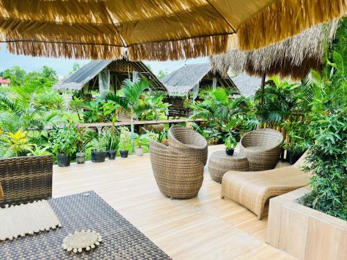 a patio with wicker chairs and tables and plants at La Palapa Inn Port Barton in San Vicente
