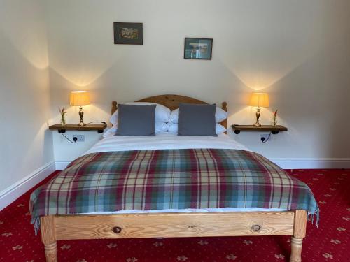 a bedroom with a bed with two lamps on two tables at The Gordon Arms Restaurant with Rooms in Yarrow