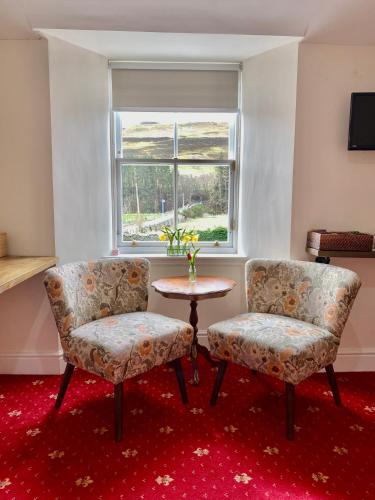 two chairs and a table in a room with a window at The Gordon Arms Restaurant with Rooms in Yarrow
