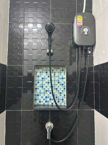 a black tiled bathroom with a shower with a hose at Blue Horizon Hostel By Blue Flow in Phi Phi Don