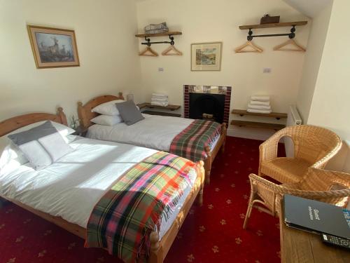 a bedroom with two beds and a fireplace at The Gordon Arms Restaurant with Rooms in Yarrow