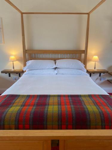 a bed with a striped blanket and two lamps on two tables at The Gordon Arms Restaurant with Rooms in Yarrow