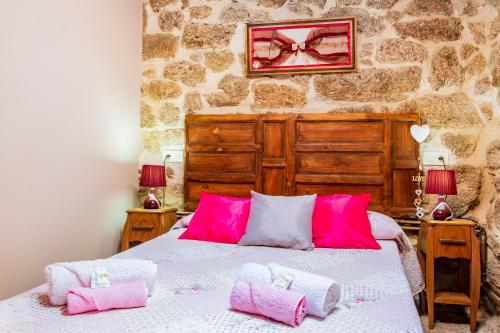 a bedroom with a bed with pink and white pillows at La Fragua in Villar de Corneja