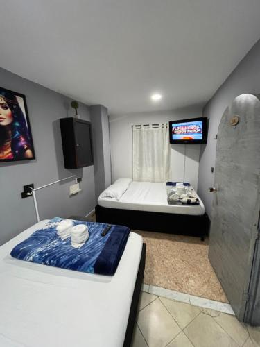 a small room with two beds and a tv at Hotel Las Vegas in Guatapé