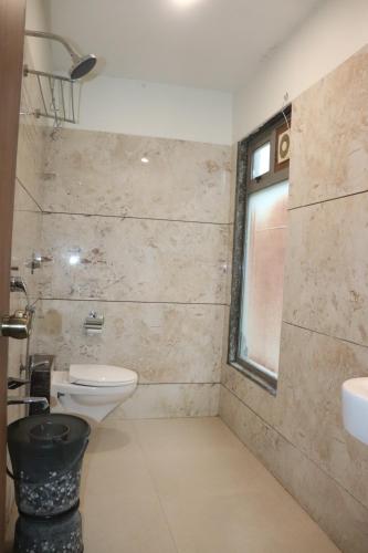 a bathroom with a toilet and a sink and a window at THE GRAND KRISHNA ROOMS Patan in Pātan