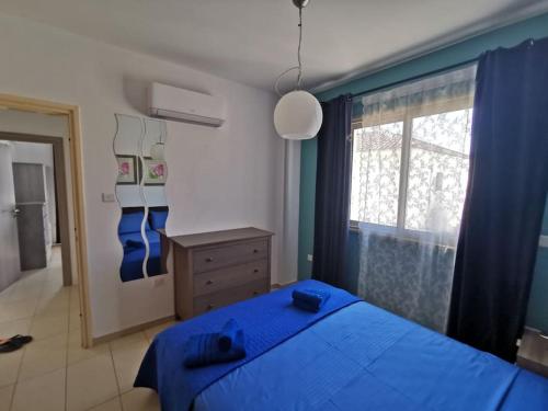 a bedroom with a blue bed and a window at Relax by the sea in Protaras