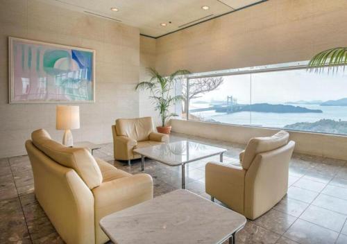 a living room with furniture and a large window at Setouchi Kojima Hotel Kurashiki in Kurashiki