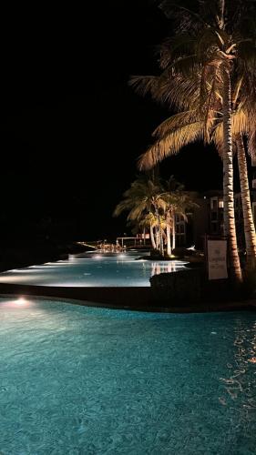 a swimming pool with palm trees at night at 2BHK furnished flat with jacuzzi in As Sīfah