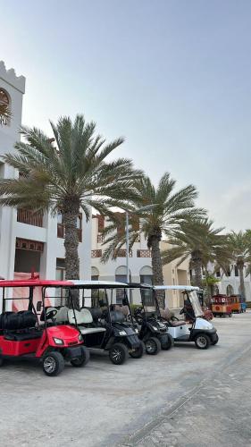 a row of golf carts parked next to palm trees at 2BHK furnished flat with jacuzzi in As Sīfah