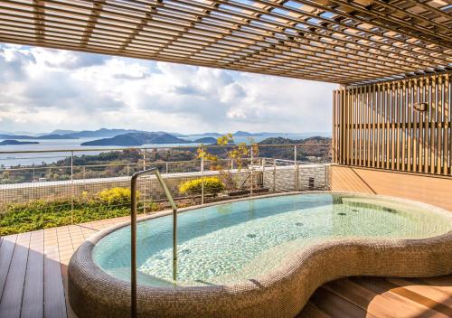 a hot tub on a deck with a view of the ocean at Setouchi Kojima Hotel Kurashiki in Kurashiki