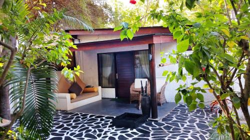 a house with a patio with a couch and trees at Scallywags Beach Club in Gili Air
