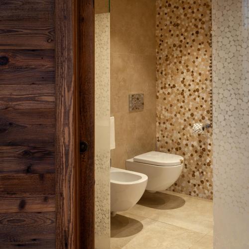 a bathroom with a toilet and a wall at Asiago Sporting Hotel & Spa in Asiago