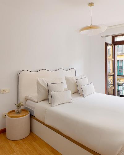 a white bedroom with a white bed with pillows at Dúplex Casco Histórico-Catedral Parking incluido in Oviedo