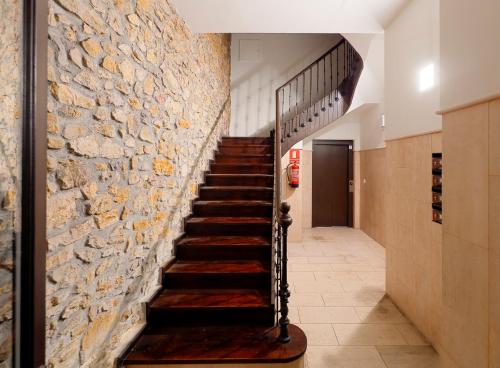 a staircase in a building with a stone wall at Dúplex Casco Histórico-Catedral Parking incluido in Oviedo
