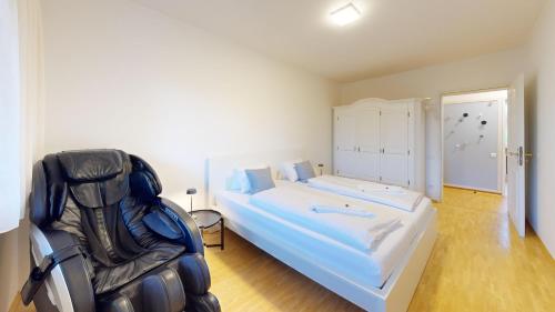 a bedroom with a bed and a chair in it at HEIMATEL - Ferienhaus Blümele in Scheidegg