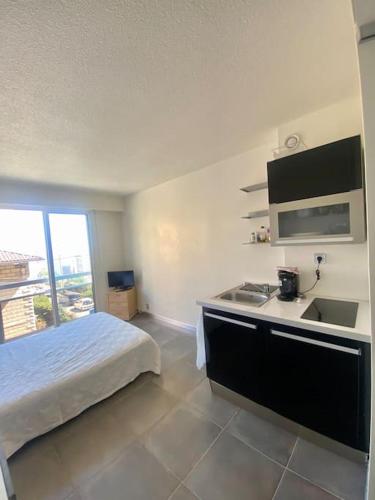 Il comprend une chambre avec un lit et une cuisine avec un évier. dans l'établissement Studio Monaco central - wifi, à Beausoleil