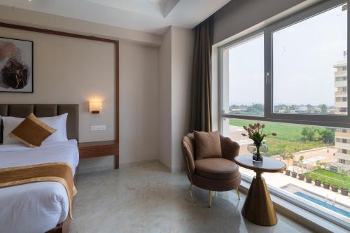 a bedroom with a bed and a chair and a window at VITS Satyajeet Karad in Karad