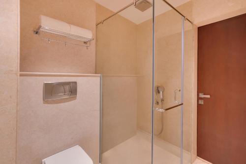 a bathroom with a glass shower with a toilet at Lemon Tree Hotel, Noida in Noida