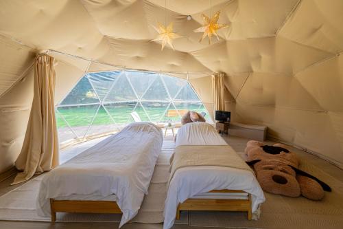 two beds in a room with a large window at glampark Healthy Pal Gunma in Shibukawa