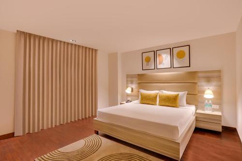 a bedroom with a large bed with yellow pillows at Lemon Tree Hotel, Noida in Noida