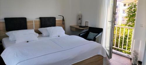 a bedroom with a white bed and a balcony at Alte Stadtmauer - Apartment in Sinsheim