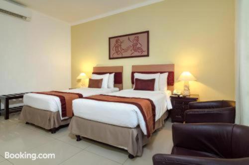 a hotel room with two beds and a couch at Sarinande Hotel in Seminyak