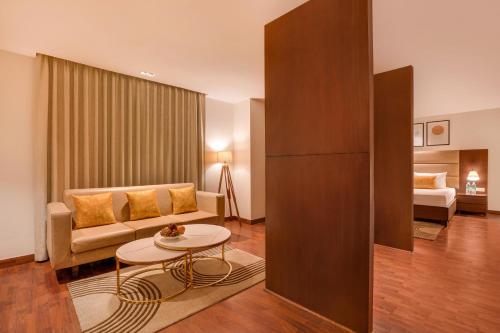 a living room with a couch and a table at Lemon Tree Hotel, Noida in Noida