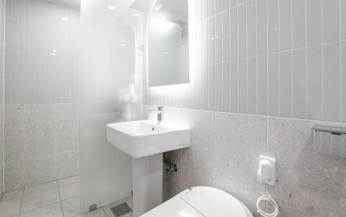 a white bathroom with a toilet and a sink at Star light Hotel in Seoul