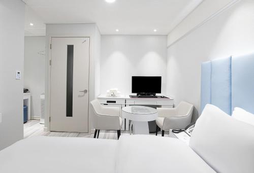 a white room with a desk with a computer and chairs at Star light Hotel in Seoul