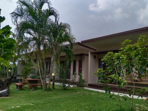 a house with a palm tree in the yard at เดอะนิรันดร์ เกสท์เฮ้าส์กาญจนบุรี in Ban Chuk Yai Yuan