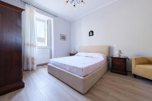 a bedroom with a bed and a chair and a window at Villamonte Colonna in Patti