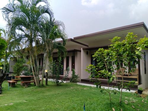 a guest house with a garden in front of it at เดอะนิรันดร์ เกสท์เฮ้าส์กาญจนบุรี in Ban Chuk Yai Yuan