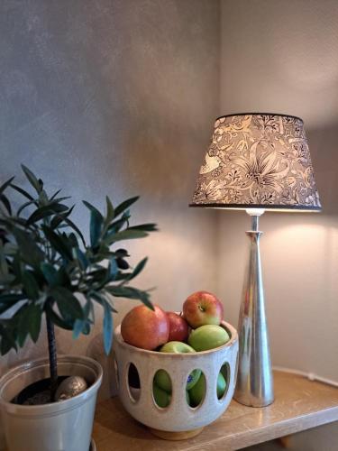 a lamp and a bowl of apples on a table with a potted plant at Hotell Rådhuset in Lidköping