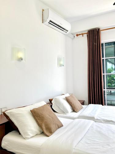 a bedroom with two beds with white sheets and a window at Aqua Sunset in Gulhi