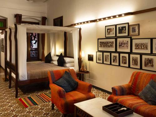 a bedroom with a canopy bed and a couch and chair at The House of MG-A Heritage Hotel, Ahmedabad in Ahmedabad