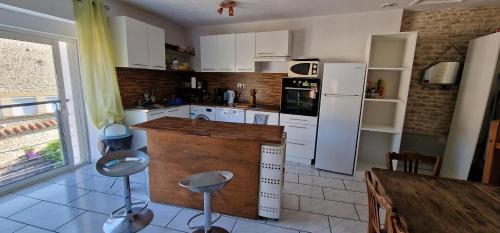 une cuisine avec des appareils électroménagers blancs et un comptoir avec des tabourets dans l'établissement Chambres d hôtes chez Georges, à Spoy