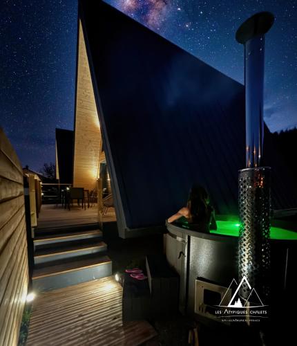 a hot tub on the roof of a house at night at Les Atypiques Chalets in Barbey-Séroux