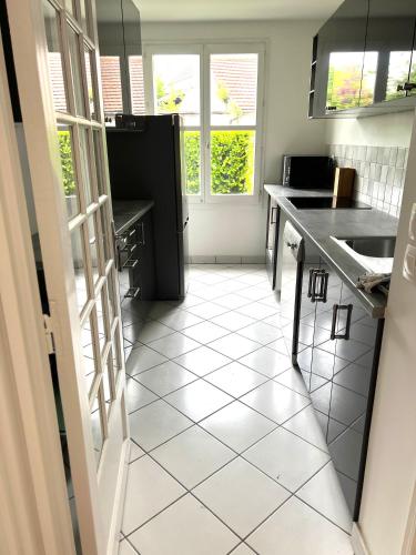 a kitchen with a white tiled floor and a sink at Appartement standing avec jardin, 4 personnes, stratégiquement situé in Mantes-la-Jolie