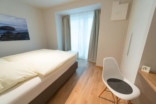 a bedroom with a bed and a chair and a window at Premium Apartments Thommen in Nürnberg