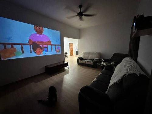 a living room with a couch and a flat screen tv at Cinematic Home Stay in Ulu Choh Village